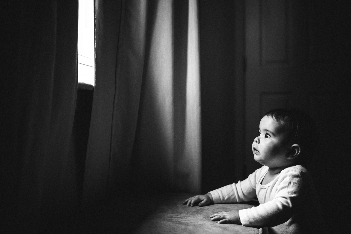 Black and white photo of a child looking out of a window