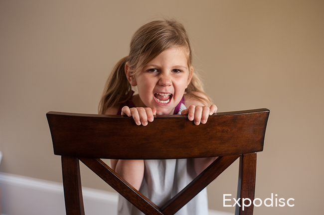 Child making a silly face in a brown chair.
