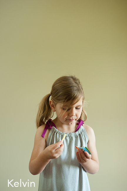 Child holding candy in a grey dress.