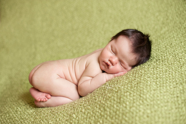 Newborn baby on green blanket.