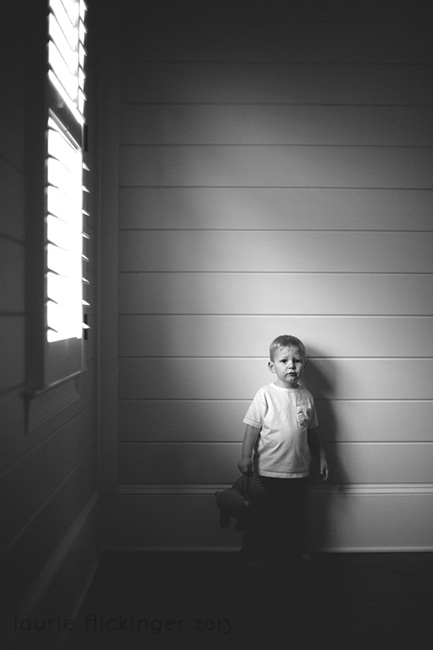Child in a white shirt standing in front of a wall with horizontal lines. The image is showing framing in photography by using a light source. 