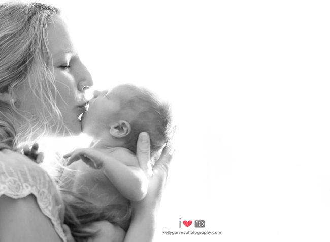 Mother and infant kissing on the left side of the frame. There is negative space filling the rest of the image. 