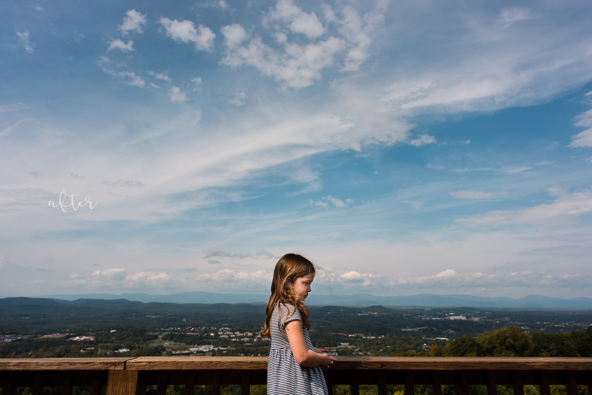 Child standing on a platform with a vast landscape in the back ground including a bright blue sky. Image shows how to properly expose faces in hard light in post processing.