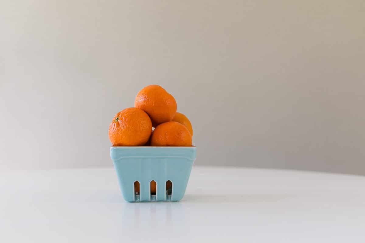 Oranges stacked in a blue container on a white table 