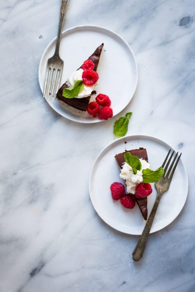 dark chocolate cake with fresh whipped cream, fresh berries on white plate taken with 50mm lens for food photography