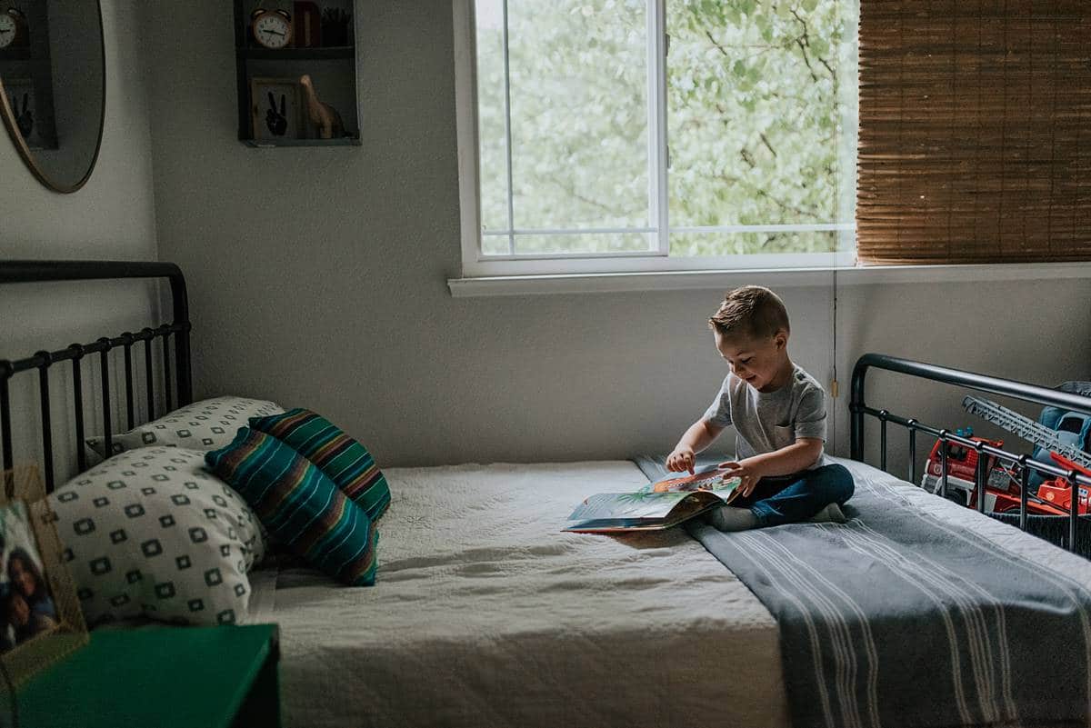 A child looking through a book on a bed as an example of lifestlye photography. 