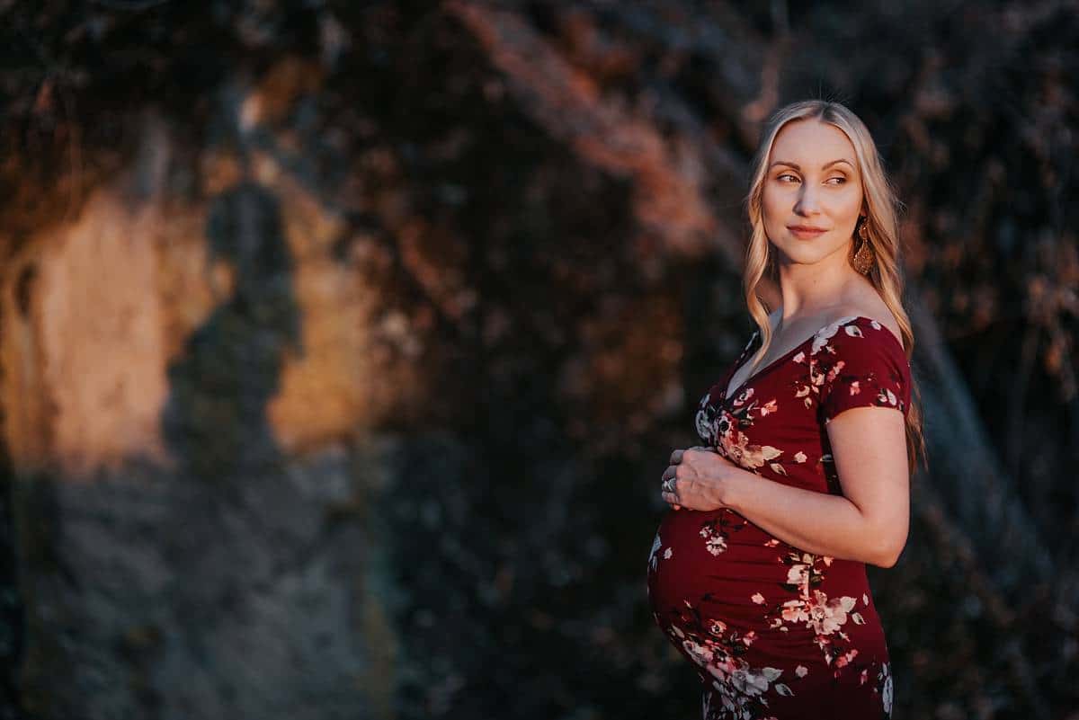 A maternity lifestyle photograph taken of a mother in a red dress.