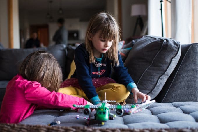 Image of children playing with airplane toy sitting on a couch. Lifestyle photography style