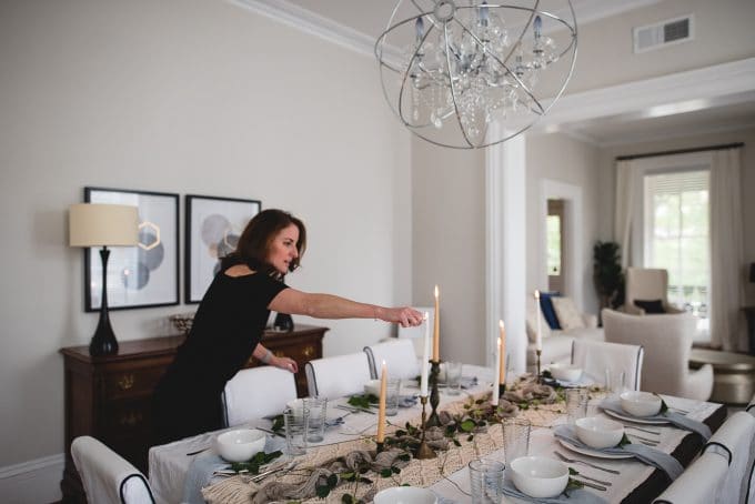 A woman lighting candles for a dinner party using all indoor natural light