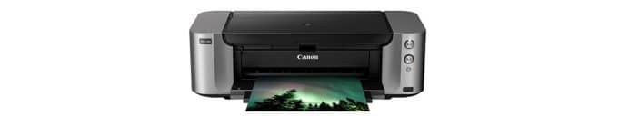 Black and gray photo printer with a silhouette image of trees amongst a green night sky.