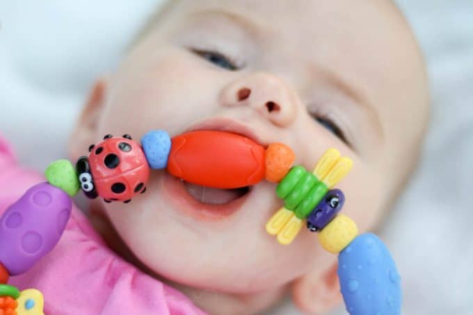 A baby chewing on a toy which is the focal point and the babies face is not in focus.