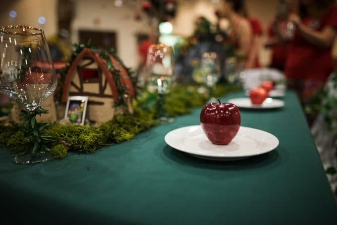 Photo of a red shiny apple on a white plate on a green table cloth to show how depth of field and apperture affects your exposure