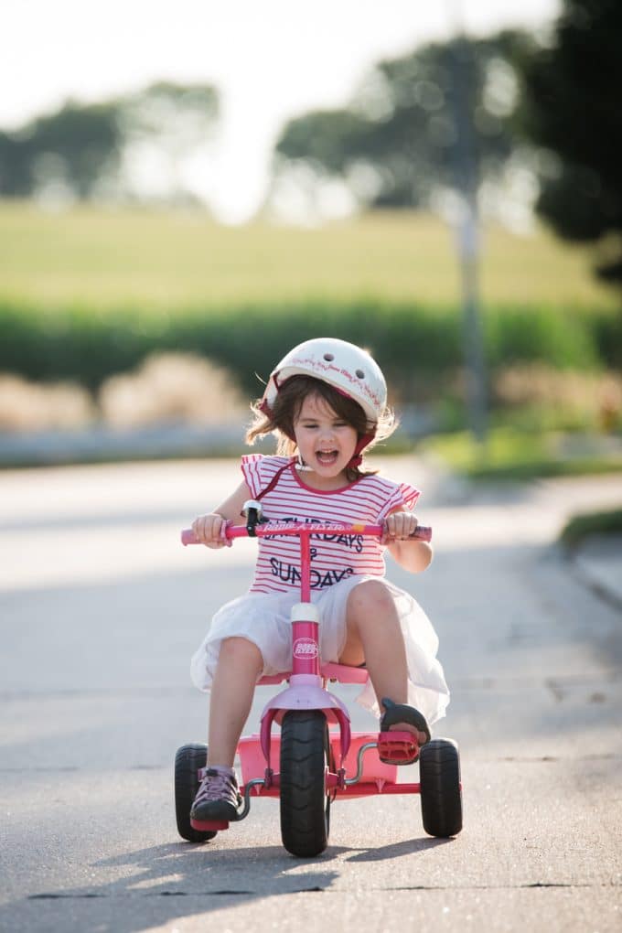 Child riding a pink tricycle. 