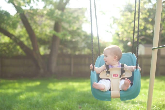 child in a blue swing with a very blurred background using a prime lens to show a lens comparison
