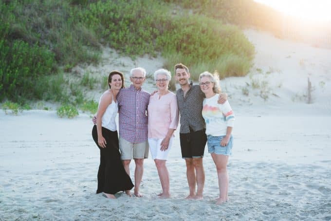 Family photo of adult children with parents in a group photo on a beach
