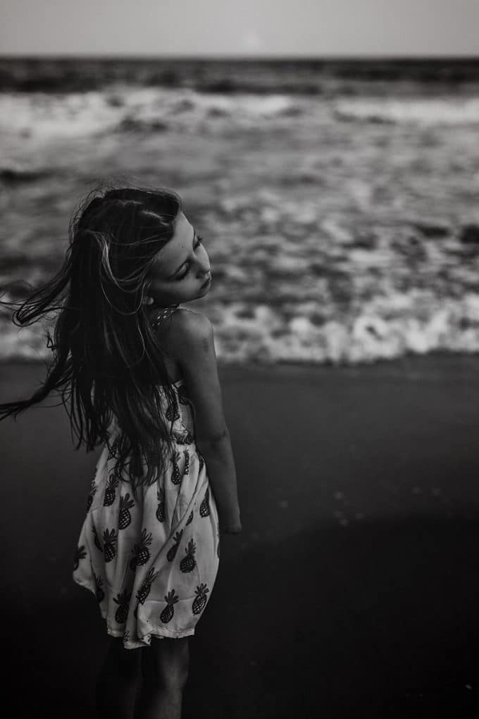 Child on beach in a white dress shot in black and white.
