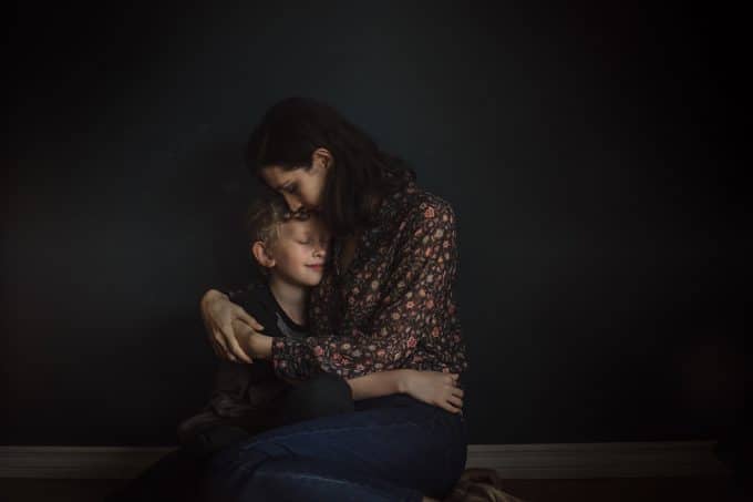 Mother and son hugging in a low light photography setting. 